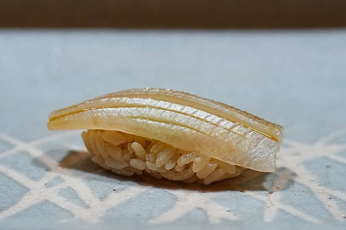 薄く繊細な切り込みが入った白身魚の握り寿司。